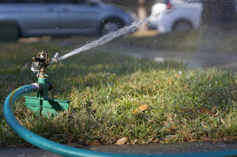 Sprinkler going off near a sidewalk