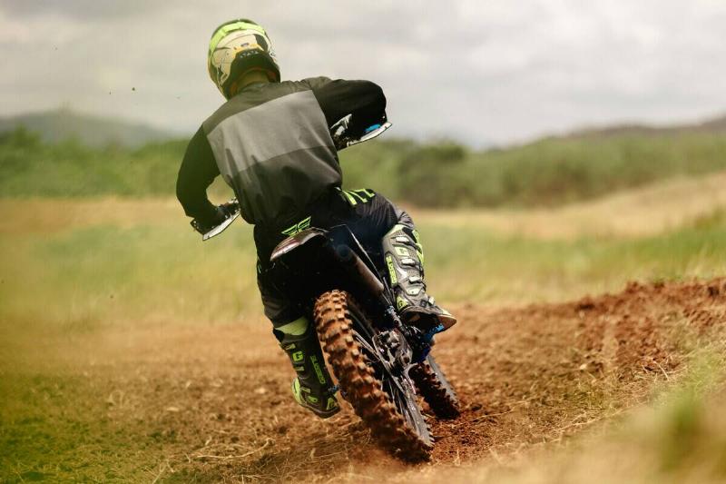 Individual writing a dirt bike across a dirt path