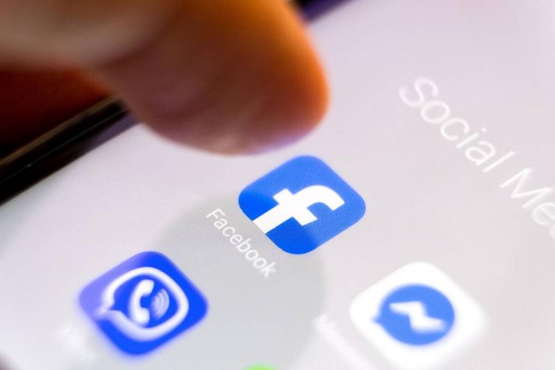 Finger hovering over the Facebook app icon on a cellphone screen