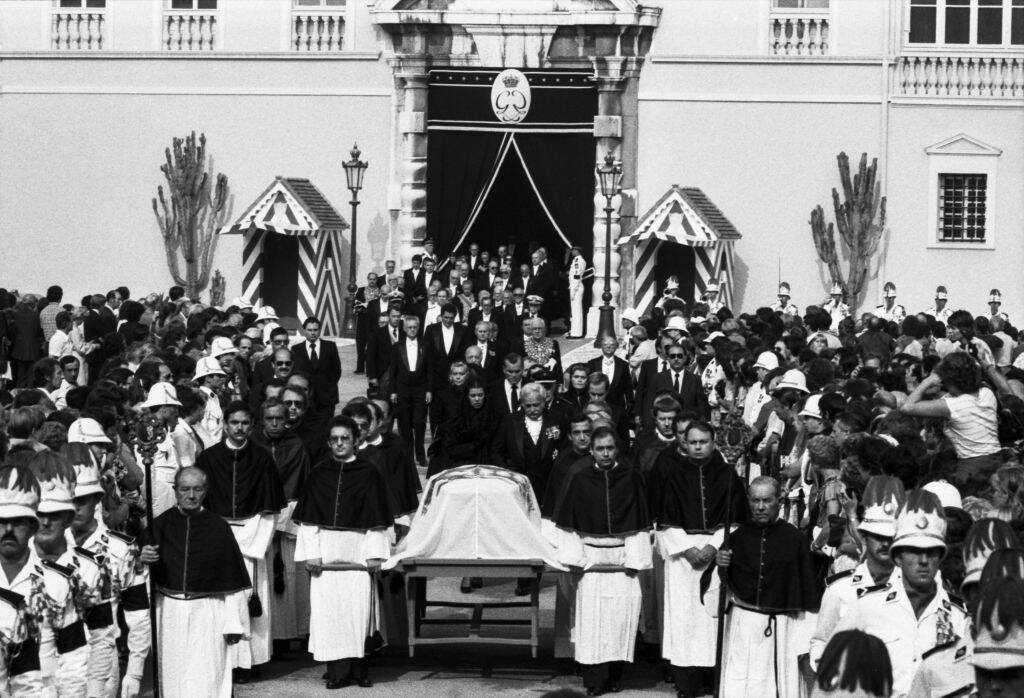 Mourners gathered around a coffin draped with a flag
