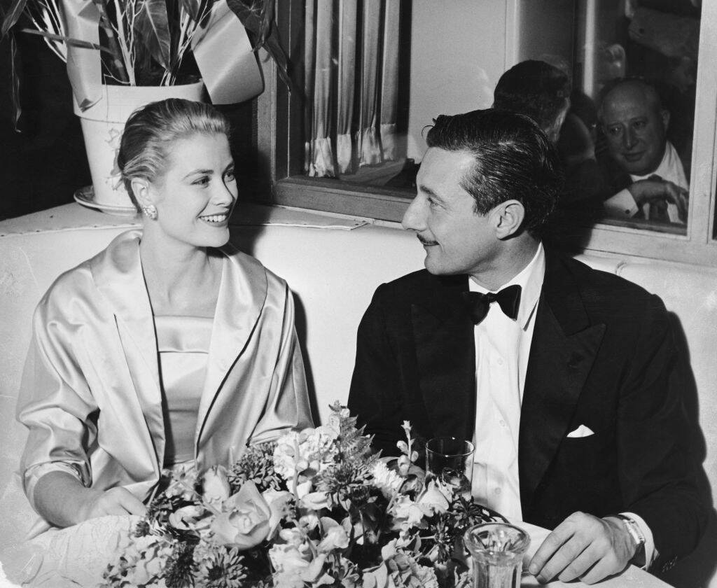 Grace Kelly and Oleg Cassini sitting together in a booth