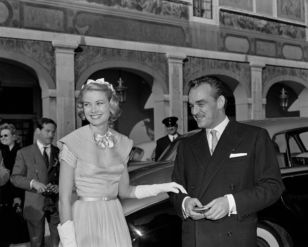 Grace Kelly and Prince Rainier standing outside of a vehicle