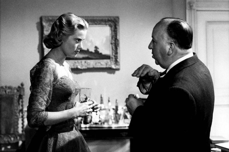 Grace Kelly and Alfred Hitchcock standing on the set for 'Dial M for Murder'