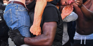 A BLM protestor carries a far-right counter-protestor to get medical help.