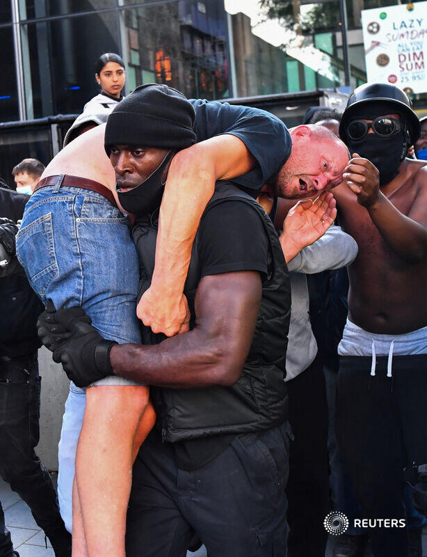 A BLM protestor carries a far-right counter-protestor to get medical help.