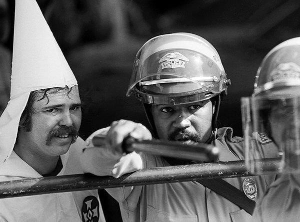 Police protect KKK member as protesters close in during a rally, Austin, Texas, circa 1983.