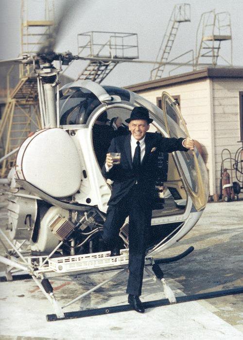 Frank Sinatra exiting a helicopter with drink in hand, 1964.