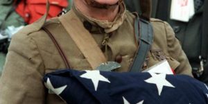 A World War I veteran holds the flag that once covered the casket of his son, who was killed in the Korean War. (1982)