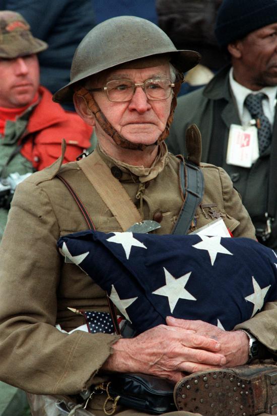 A World War I veteran holds the flag that once covered the casket of his son, who was killed in the Korean War. (1982)