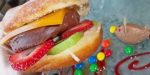 Nutella Burger ‘“ warm donut, Nutella mousse, passion fruit gelatin, fresh strawberries and kiwi.