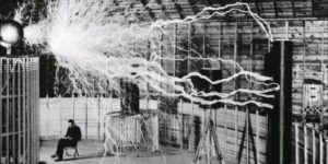 Nikola Tesla sitting in his laboratory with his Magnifying Transmitter