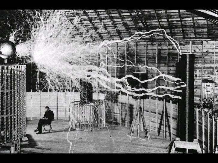 Nikola Tesla sitting in his laboratory with his Magnifying Transmitter