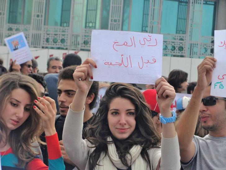 Tunisian Protester holding A Sign That Says Grow The Brain Before The Beard