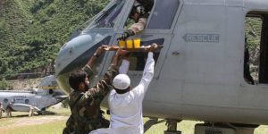 Pakistani military personal and civilian offer fruit juice and cookies to a US marine during the 2010 floods