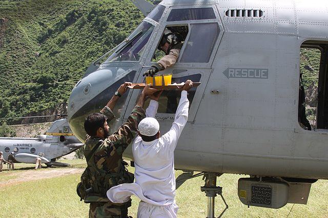 Pakistani military personal and civilian offer fruit juice and cookies to a US marine during the 2010 floods