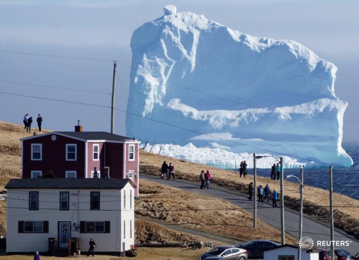 Residents watch an iceberg as it passes "Iceberg Alley" in Newfoundland, Canada