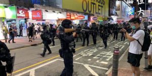 Chinese police and Hong Kong journalists flex their weapons at each other.