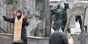 Orthodox priest attempting to prevent a clash between protesters and police in Kiev, Ukraine, 2014.