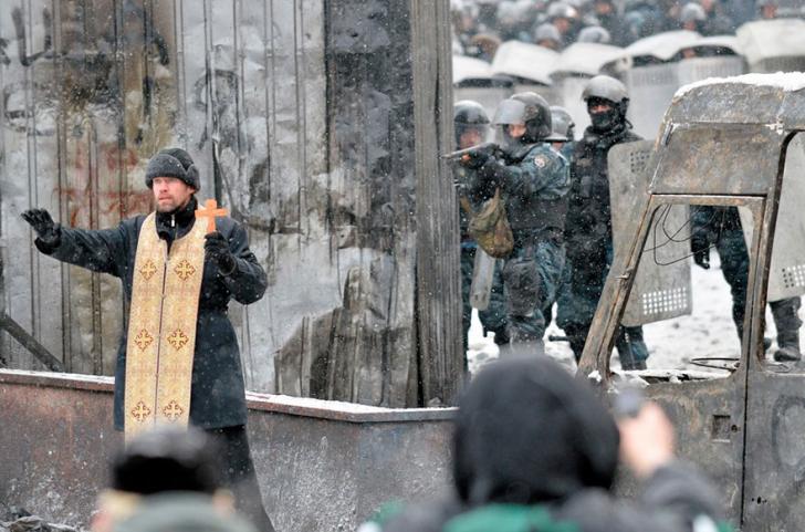 Orthodox priest attempting to prevent a clash between protesters and police in Kiev, Ukraine, 2014.
