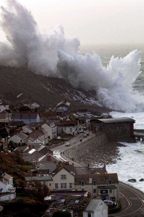 A wave craches over the cliffs at sennen cove in Cornwall
