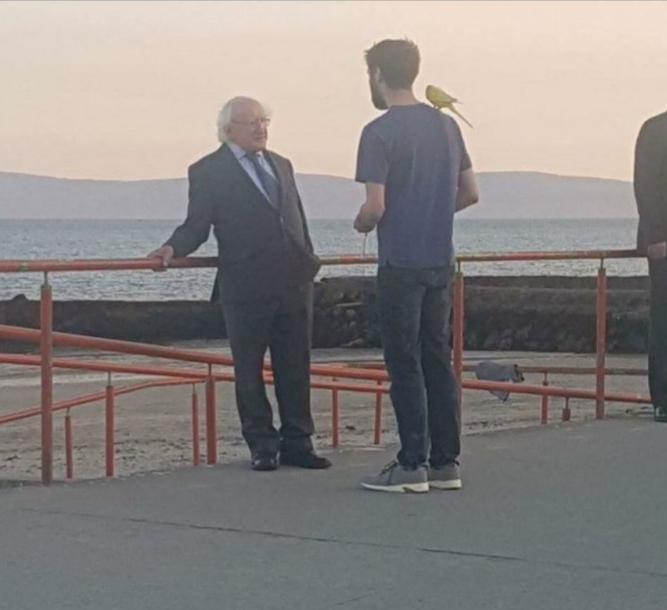 The President of Ireland ominously talking to the man with a parrot.
