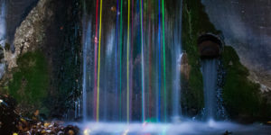 Long exposure shot of glow sticks dropped into a waterfall.