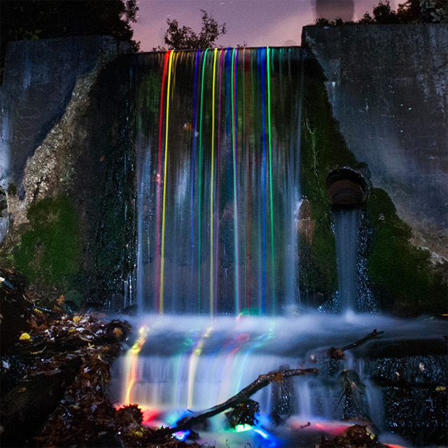 Long exposure shot of glow sticks dropped into a waterfall.