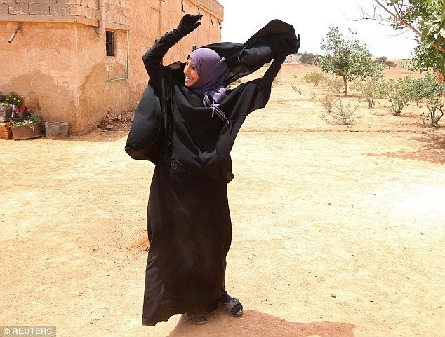 Removing a niqab after her city is freed from Isis control