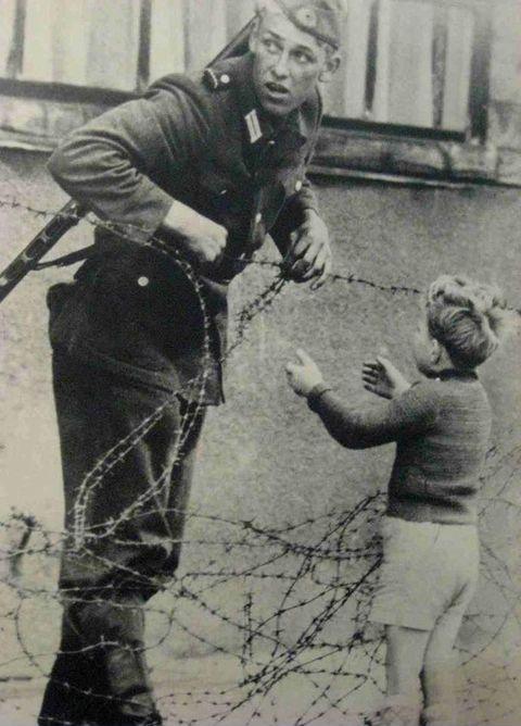This moment.. An East German soldier ignores orders to let no one pass and helps a boy