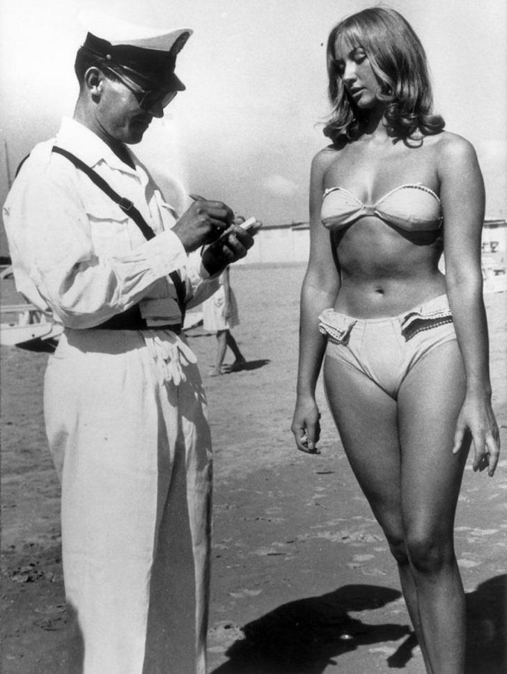 A Police officer issuing a woman a ticket for wearing a bikini on a beach at Rimini, Italy, in 1957