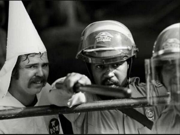 Officer protects a KKK member from protesters.