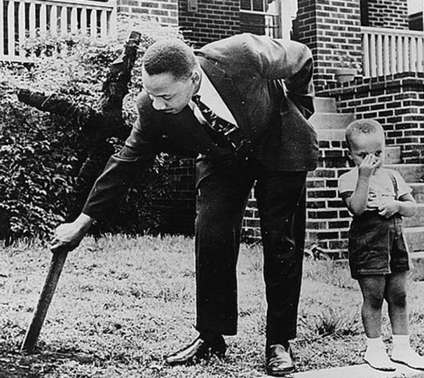 Martin Luther King Jr. with his son by his side removing a burnt cross from his front yard, 1960