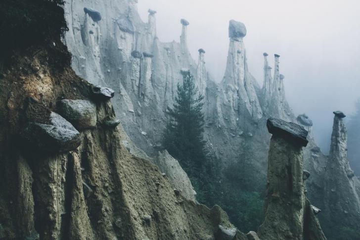 Rocks perched on eroded pillars of dirt in the Italian Alps