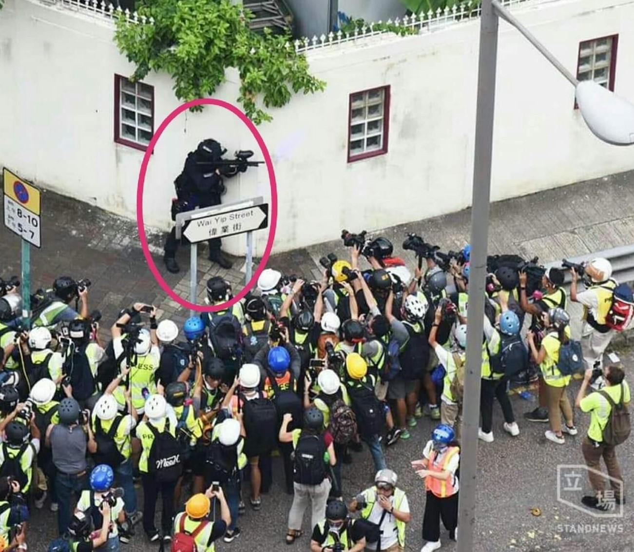 Police Officer (encircled) Surrounded by Photographers in Hong Kong